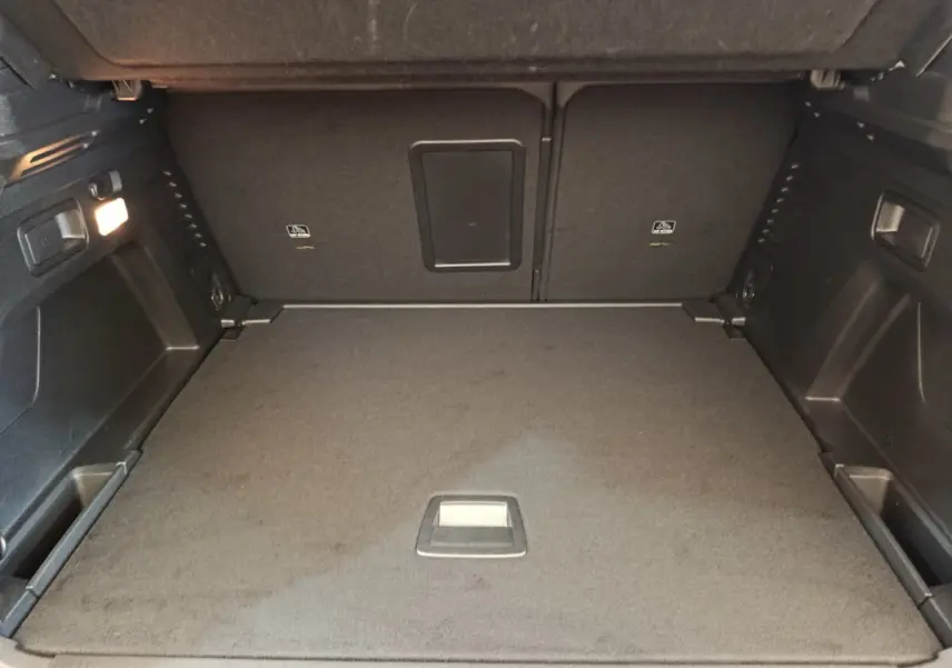 Coffre ouvert vu de face du Peugeot 3008 rouge 2022, espace de rangement avec plancher plat et éclairage intérieur.