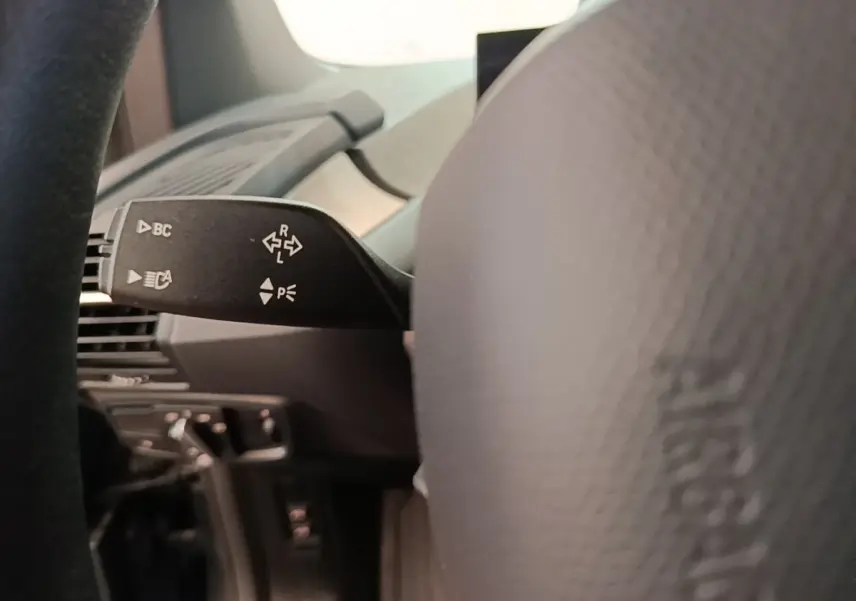 Gros plan sur la manette de clignotant à gauche du volant dans l'habitacle d'une BMW i3 noire 2020.