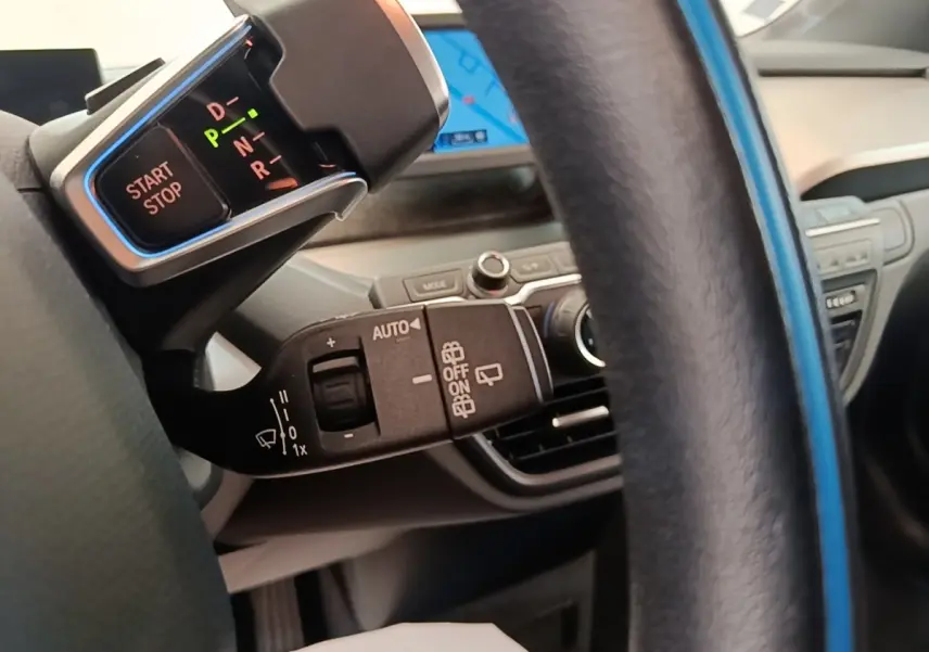 Gros plan sur la commande de boîte automatique et bouton start/stop à gauche du volant cuir noir d'une BMW i3 120 Ah Atelier 2020.