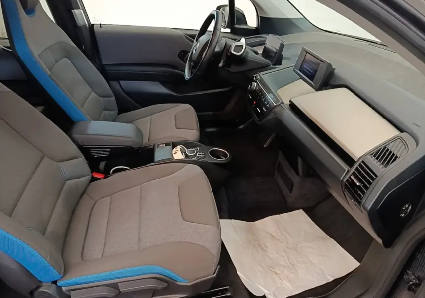 Vue intérieure côté conducteur de la BMW i3 120 Ah Atelier 2020, sièges gris avec surpiqûres bleues et tableau de bord moderne.
