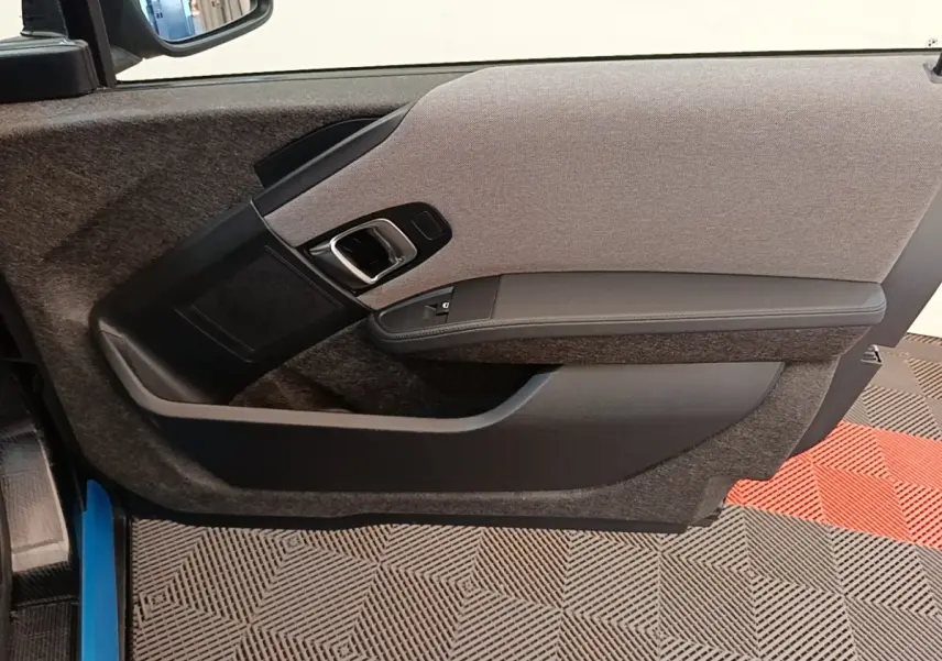 Vue intérieure de la porte côté gauche d'une BMW i3 120 Ah noire, avec habillage tissu gris et accoudoir noir.