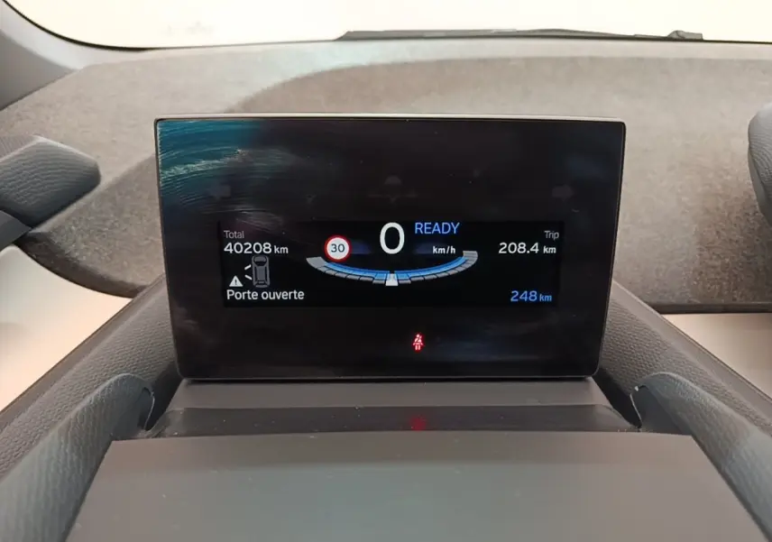 Affichage numérique du tableau de bord de la BMW i3 120 Ah Atelier montrant vitesse, autonomie et porte ouverte.