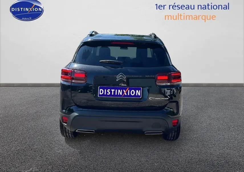Vue arrière d'un Citroën C5 Aircross noir 2025 avec barres de toit et feux LED allumés sur sol goudronné.