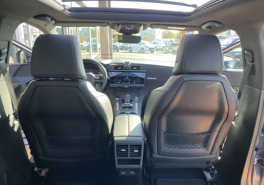 Vue intérieure arrière du DS7 gris Artens, montrant les sièges avant en cuir noir et la console centrale avec écran tactile.
