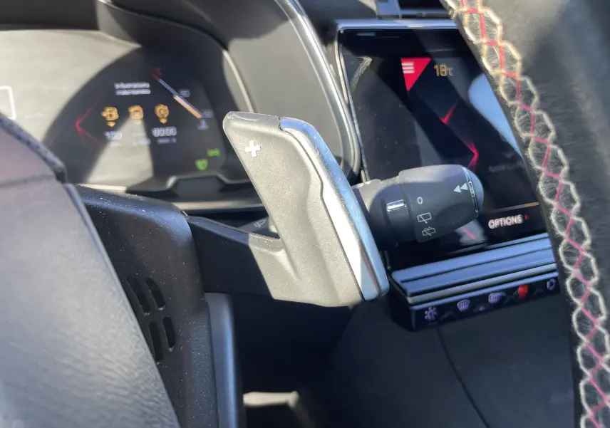 Gros plan sur la palette de changement de vitesse droite et le tableau de bord numérique du DS7 gris Artens, intérieur moderne avec écran tactile.