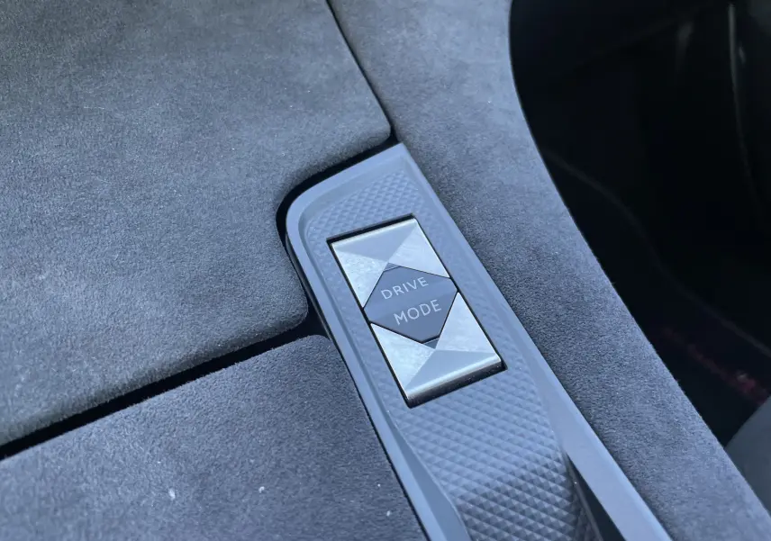 Bouton Drive Mode en gros plan sur la console centrale recouverte de tissu gris foncé dans l'habitacle du DS7 gris Artens.