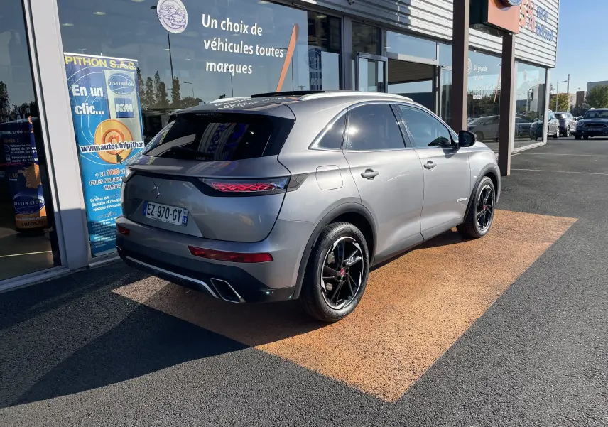 Vue 3/4 arrière droite du DS7 gris Artens, soulignant ses feux arrière LED et ses jantes noires brillantes.