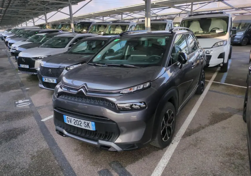 Citroën C3 Aircross gris foncé vue 3/4 avant droit, avec jantes alliage et toit noir brillant sous abri.