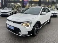 KIA Niro EV 204 CV Active blanc en 3/4 avant droit, avec phares LED et jantes noires, sur parking extérieur.