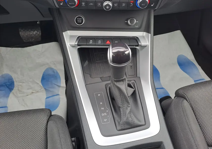 Vue rapprochée de la console centrale de l'Audi Q3 35 TDI 2023, avec levier de vitesse automatique et finition noire.