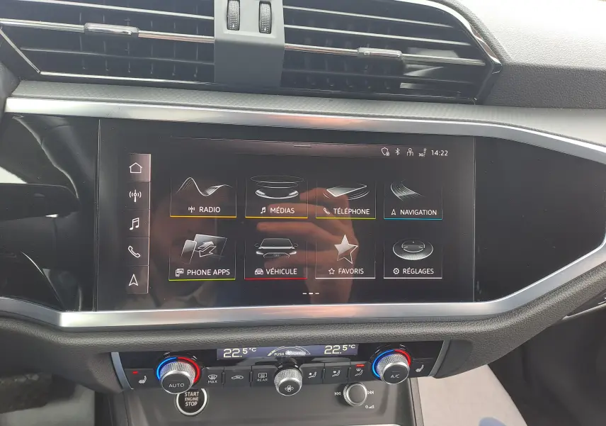 Vue rapprochée de l’écran tactile central et de la console de climatisation de l’Audi Q3 35 TDI gris Nano, intérieur noir.