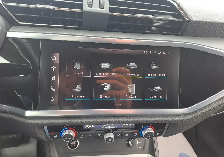 Vue rapprochée de l'écran tactile central et de la console de climatisation du tableau de bord de l'Audi Q3 gris nano 2023.