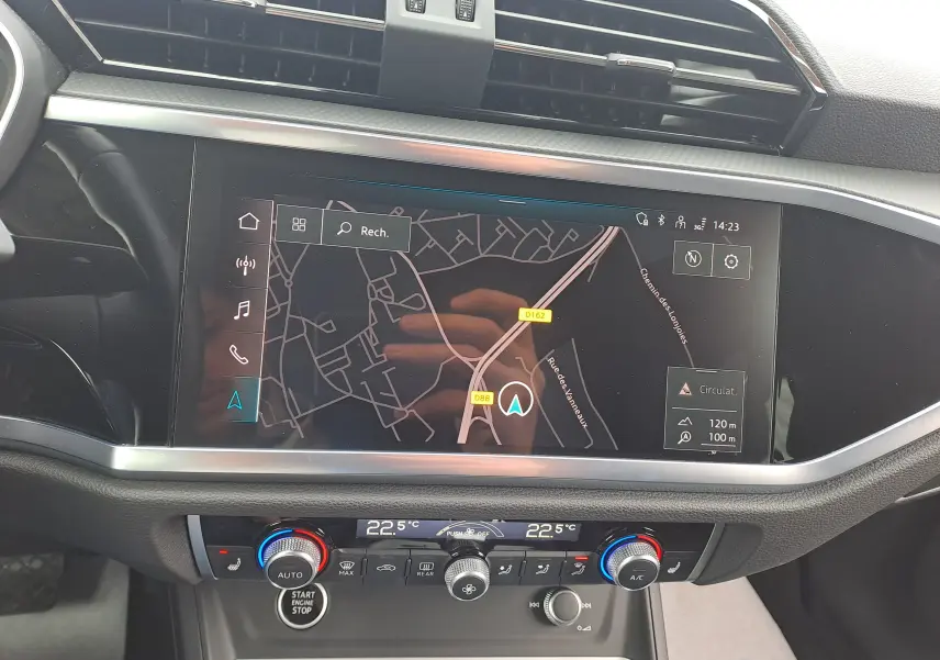 Vue rapprochée du tableau de bord de l'Audi Q3 35 TDI 2023 avec écran GPS et commandes de climatisation digitales.