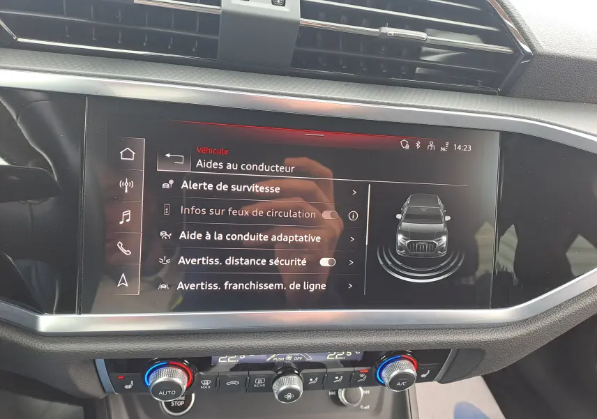 Écran tactile central de l'Audi Q3 35 TDI gris nano montrant les aides à la conduite avec commandes climatisation en dessous.