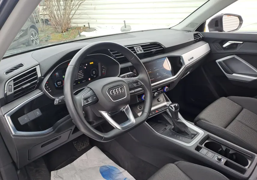 Intérieur noir de l'Audi Q3 35 TDI 2023 vu côté conducteur, avec tableau de bord digital et console centrale moderne.
