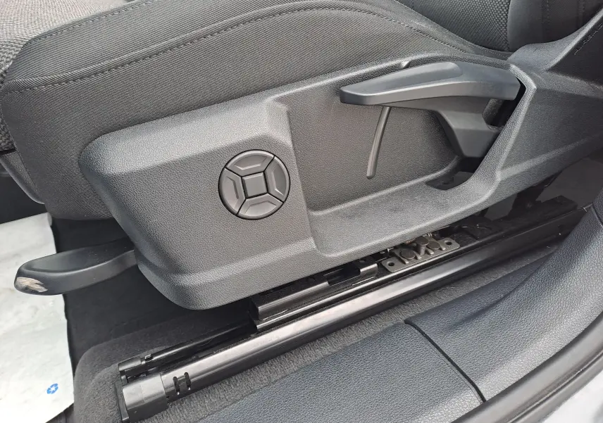 Détail du côté gauche du siège avant en tissu noir de l'Audi Q3 35 TDI 2023 avec commandes manuelles de réglage.