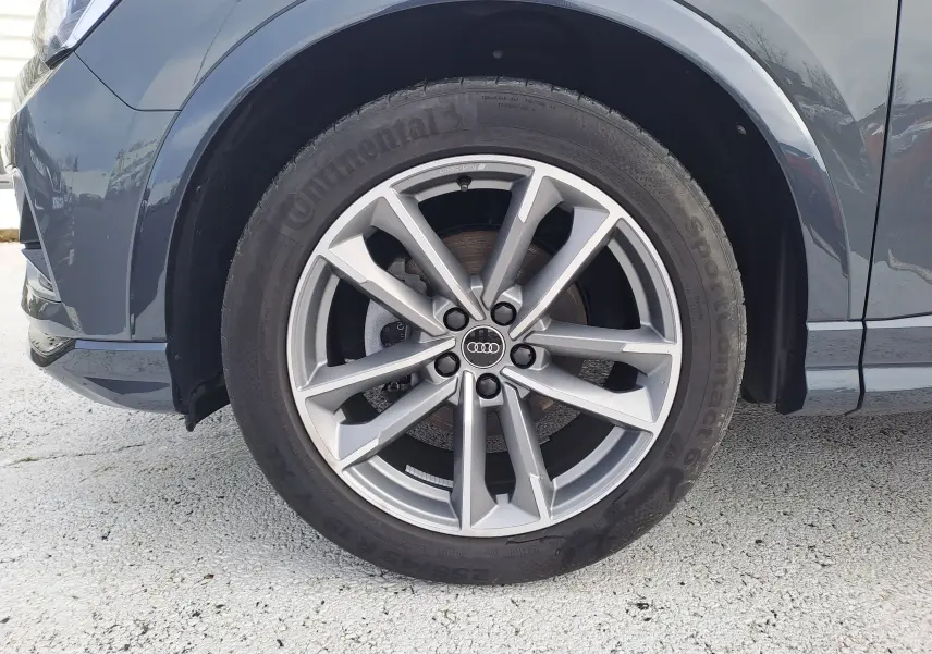 Gros plan sur la roue avant gauche avec jante alu 19 pouces du SUV Audi Q3 gris nano 2023.