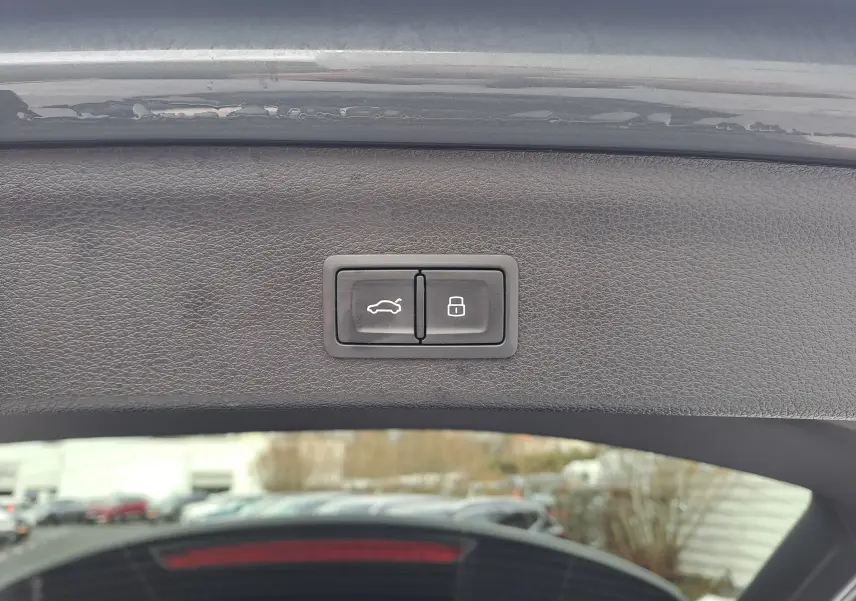 Gros plan sur les boutons d’ouverture et de verrouillage du hayon d’un Audi Q3 gris nano, vue intérieure arrière.