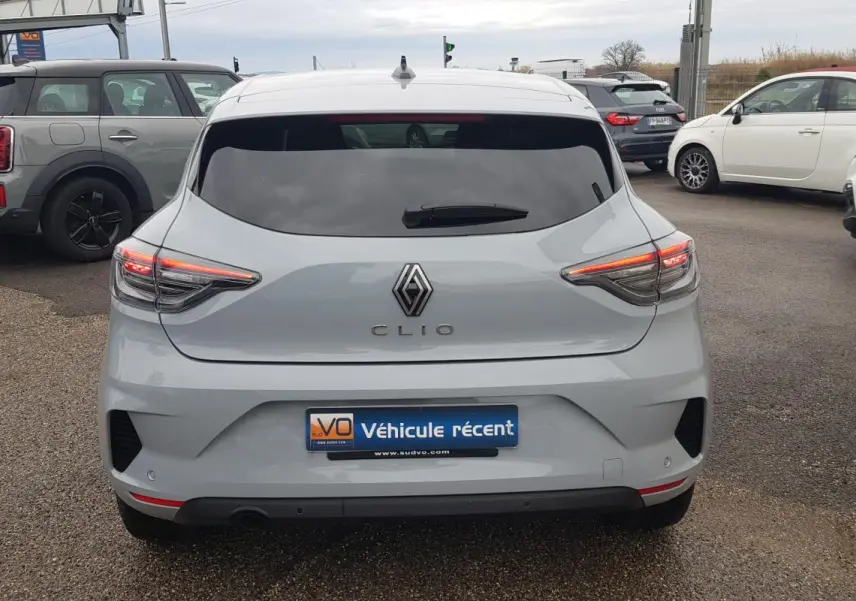 Vue arrière d'une Renault Clio gris clair 2025 avec feux LED allumés et vitres surteintées en stationnement.