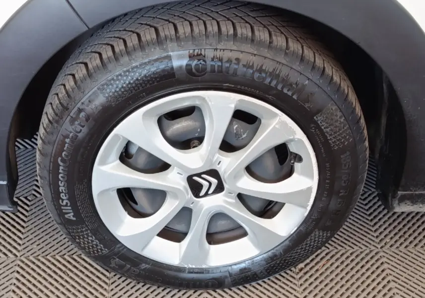 Gros plan sur la roue avant gauche d'une Citroën C3 blanche avec jante en alliage et logo Citroën central.