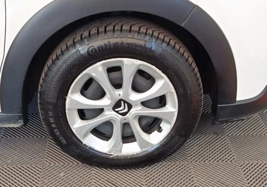 Gros plan sur la roue avant droite d'une Citroën C3 blanche avec jante argentée et logo Citroën au centre.