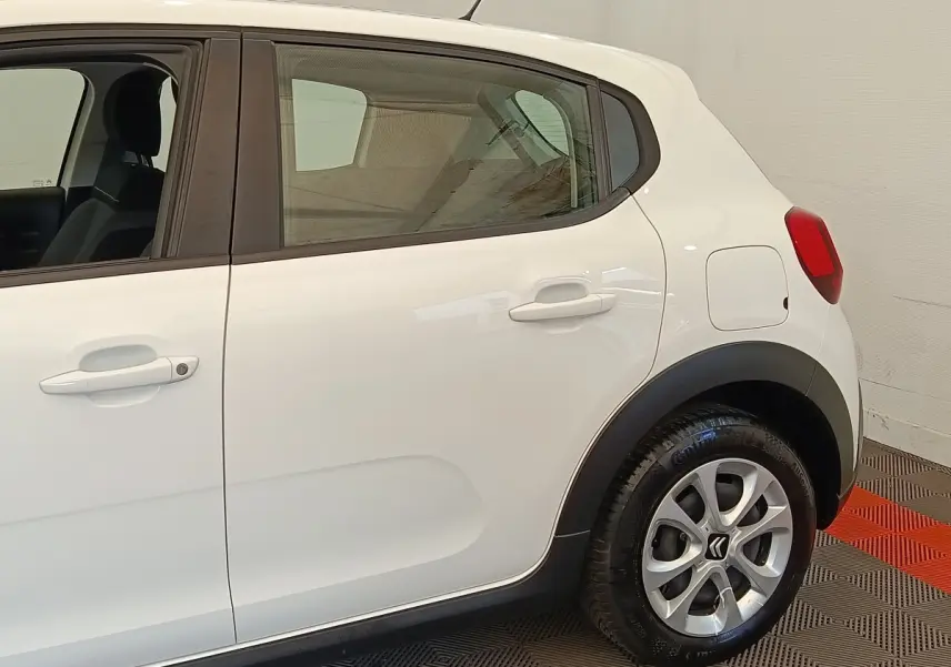 Vue latérale côté gauche d'une Citroën C3 blanche, mettant en valeur les poignées de porte et la roue arrière.