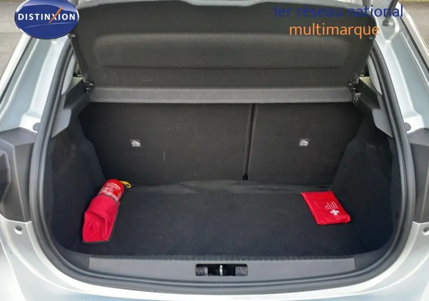 Coffre ouvert d'une Opel Corsa gris kristall metal 2022, montrant un extincteur et une trousse de secours rouges.