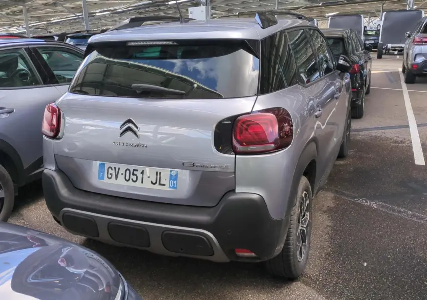 Vue 3/4 arrière droite d'un Citroën C3 Aircross gris foncé avec feux arrière rouges et jantes alliage 16 pouces.