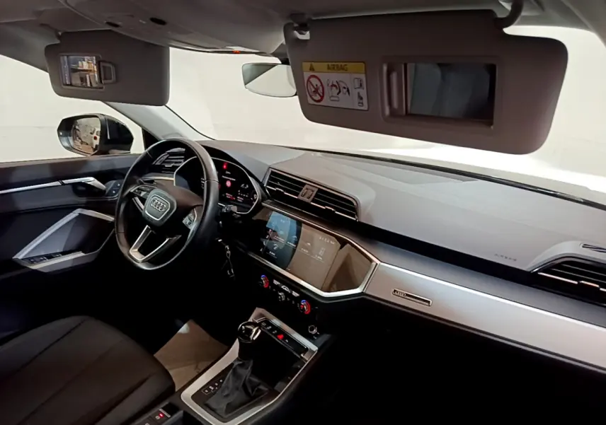 Intérieur de l'Audi Q3 35 TDI 2021 vu côté conducteur, tableau de bord moderne avec écran tactile et volant cuir noir.