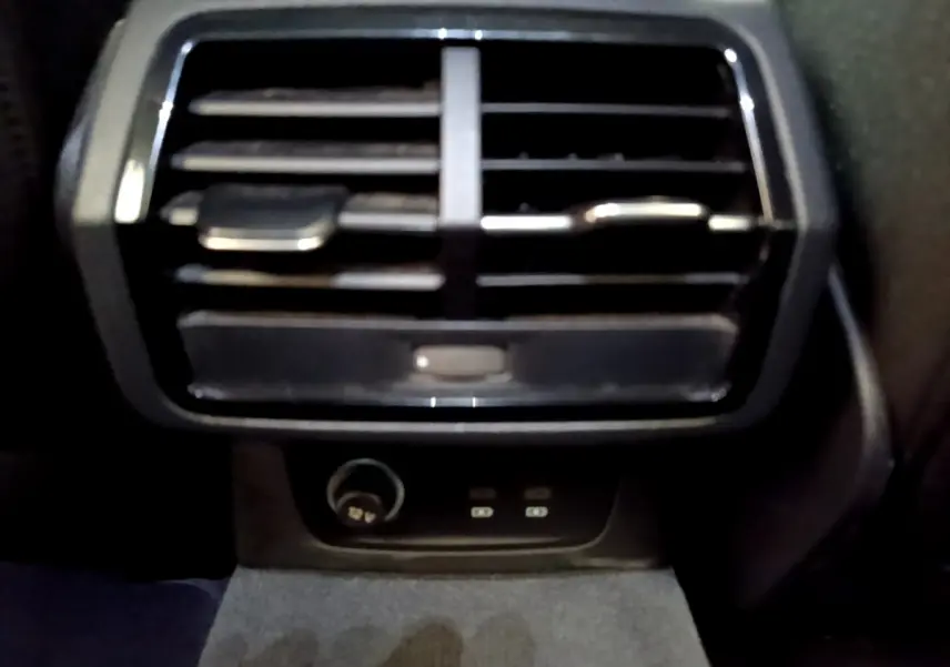 Gros plan sur la sortie d'air arrière noire et prise 12V du coffre de l'Audi Q3 35 TDI 150 S Tronic Business Line 2021.