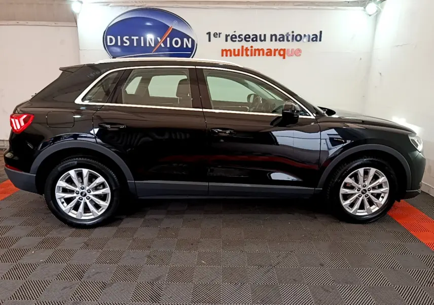 Profil côté gauche d'un Audi Q3 noir 2021 garé en intérieur avec jantes alliage et feux arrière LED allumés.