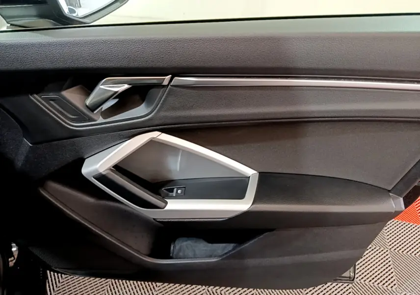 Gros plan sur la porte intérieure côté gauche noire de l'Audi Q3 35 TDI 2021 avec poignée argentée et commande de fenêtre.