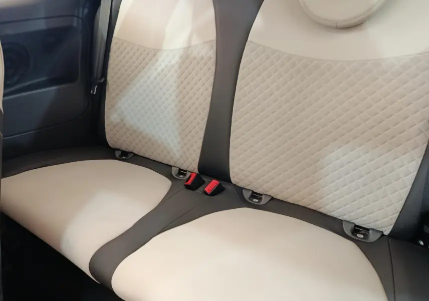 Vue rapprochée de la banquette arrière beige et noire de la Fiat 500 Hybrid Dolcevita 2022, avec ceintures visibles.