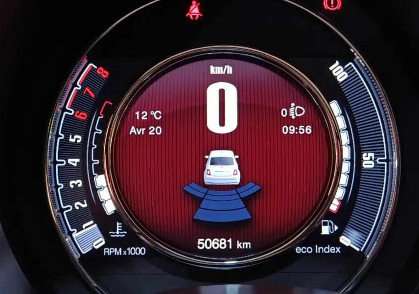 Vue rapprochée du tableau de bord numérique de la FIAT 500 blanche, affichant la vitesse à 0 km/h et l'indicateur de distance.