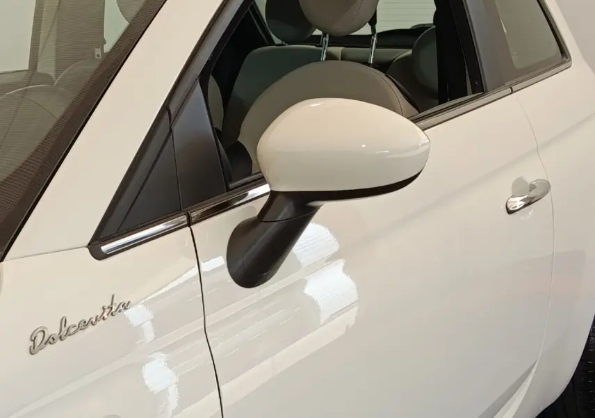Gros plan sur la porte côté gauche blanche d'une Fiat 500 Dolcevita avec rétroviseur et logo distinctif.