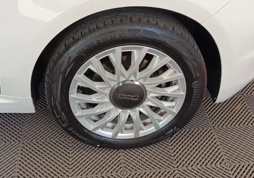 Gros plan sur la roue avant droite blanche d'une FIAT 500 Hybrid 2022 avec jante argentée à motifs fins.