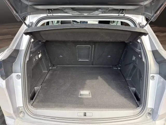 Vue arrière ouverte de la Peugeot 208 gris platinium, coffre vide et banquette arrière visible à l'intérieur.