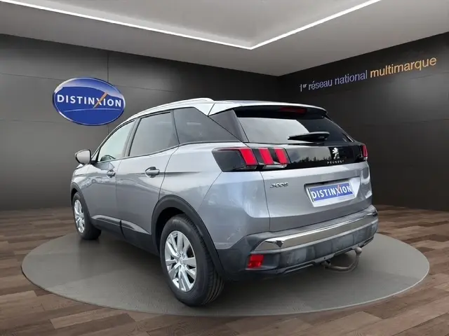 Peugeot 208 gris platinium vue 3/4 arrière droit dans un showroom avec jantes alliage et feux arrière LED.