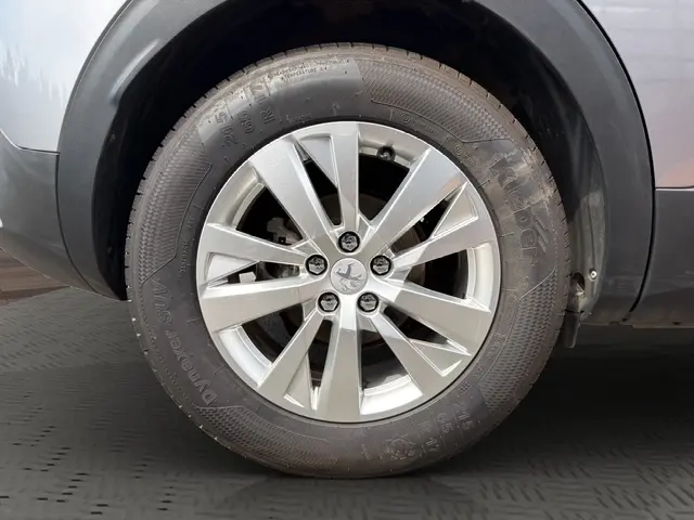 Gros plan sur la roue avant gauche d'une Peugeot 208 gris platinium, mettant en valeur la jante alliage à 5 branches doubles.