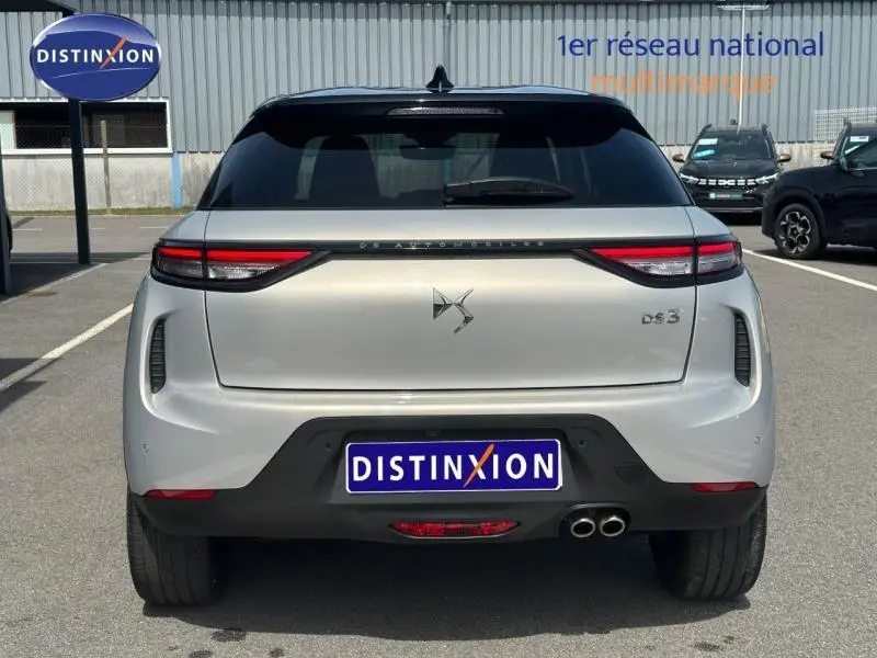 Vue arrière d'une DS3 2024 Cristal Pearl avec toit noir, feux LED effilés et double sortie d'échappement chromée.