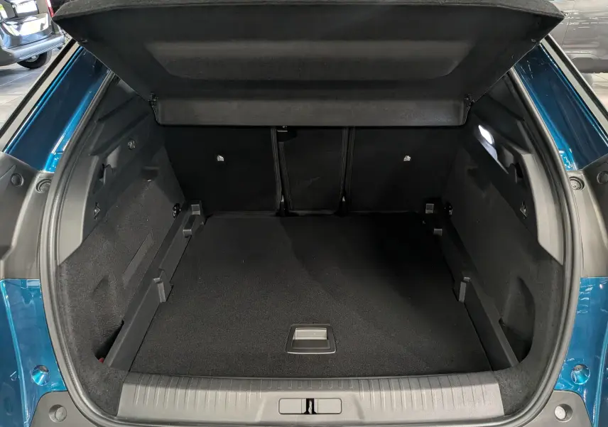 Coffre ouvert vu de l'arrière d'un Peugeot 3008 Hybrid bleu Obsession, montrant un espace de chargement propre et spacieux.