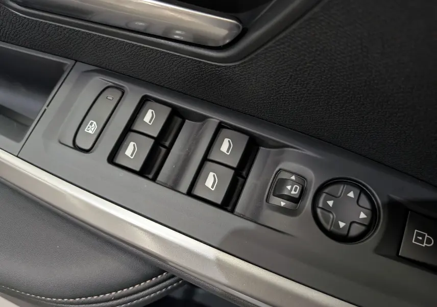 Gros plan sur les commandes de lève-vitres et réglage des rétroviseurs côté gauche d’un Peugeot 3008 Bleu Obsession.
