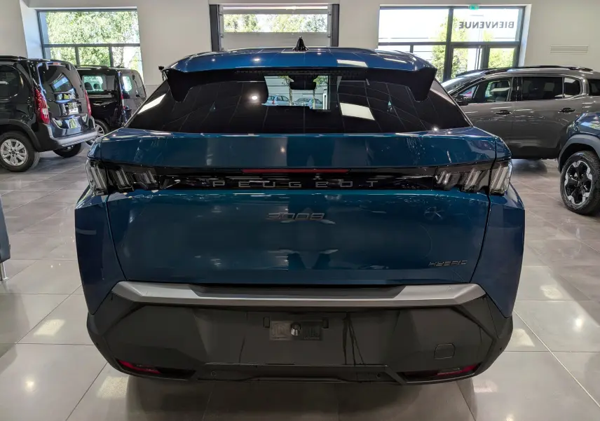 Vue arrière d’un Peugeot 3008 Hybrid 145 CH e-DCS6 Allure en Bleu Obsession, avec feux arrière noirs et logo centré lumineux.