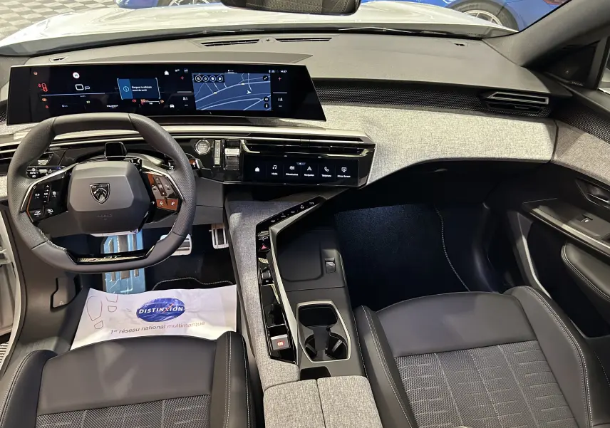 Vue intérieure avant du Peugeot 3008 Hybrid blanc Okenite, mettant en valeur le tableau de bord numérique et la console centrale moderne.