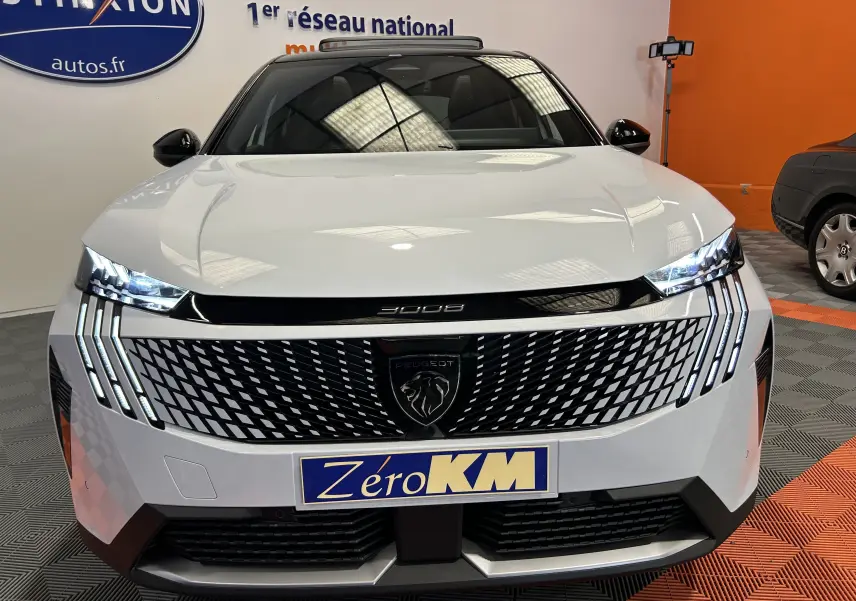 Vue frontale d’un Peugeot 3008 III Hybrid blanc Okenite avec calandre noire à motif géométrique et phares LED allumés.