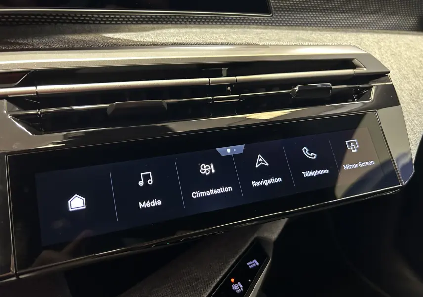 Gros plan sur l'écran tactile central noir et la sortie d'air supérieure du tableau de bord du Peugeot 3008 blanc Okenite.
