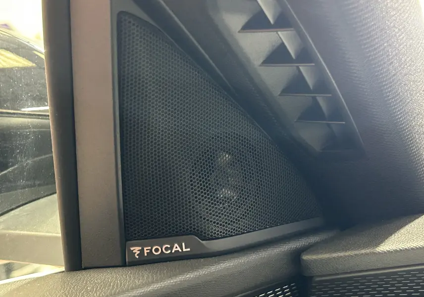 Gros plan sur l'enceinte Focal noire intégrée côté gauche dans l'habitacle du Peugeot 3008 blanc Okenite.