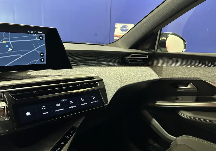 Vue intérieure côté passager du tableau de bord et de la porte d’une Peugeot 3008 III Hybrid blanc Okenite avec écran tactile et finitions tissu gris.