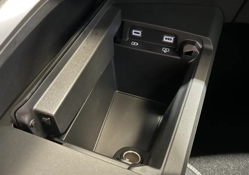 Vue rapprochée de la console centrale noire du Peugeot 3008 Hybrid avec ports USB et prise 12V intégrés.