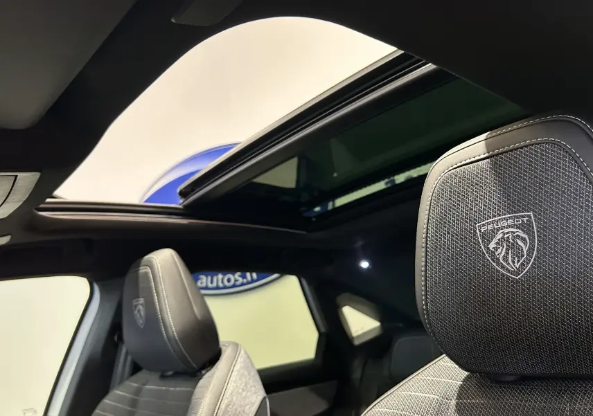 Intérieur du Peugeot 3008 Hybrid blanc, vue sur les sièges avant avec logo Peugeot et toit ouvrant panoramique.